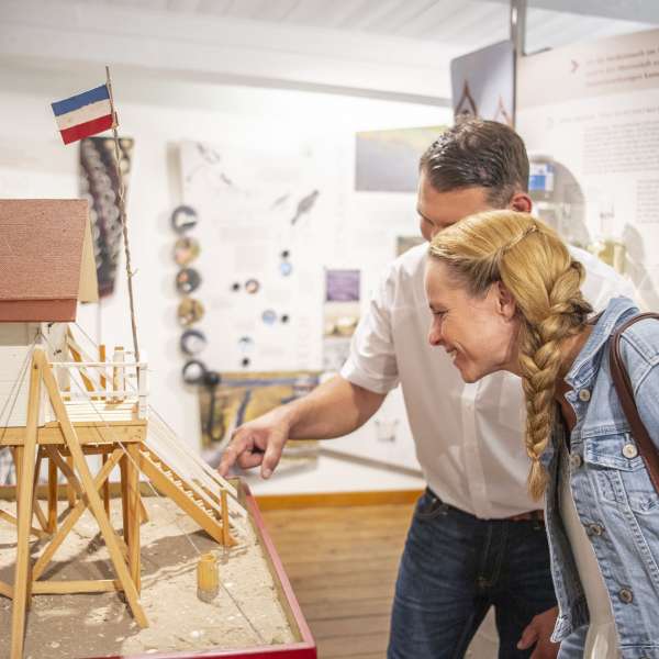 Gæster på Museum Landschaft Eiderstedt beundrer modeller af pælebygninger